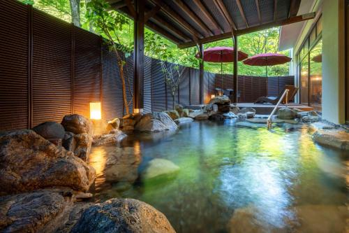 a pool in a house with rocks in the water at Yamanaka Onsen Kajikaso - Opening in 1st, Aug 2025 in Kaga