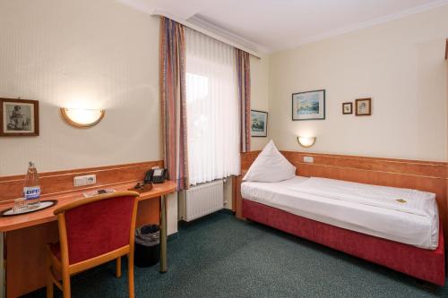 a hotel room with a bed and a desk with a telephone at Moselstern Hotel Brixiade &Triton in Cochem