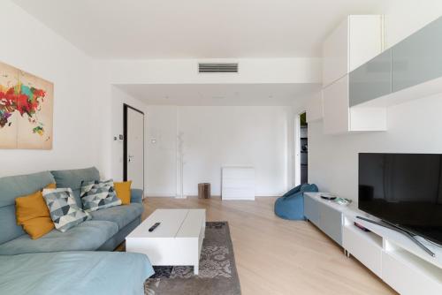 a living room with a blue couch and a tv at GuestHost - Milano 2 Bright Apartment in Vimodrone