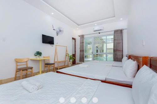 a bedroom with two beds and a desk and a television at Villages Đường Thùy Vân Bãi Sau Gần Biển in Vung Tau