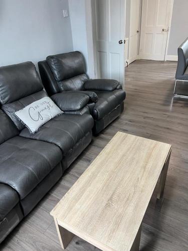 a black leather couch and a coffee table in a living room at Kings Room in Slough