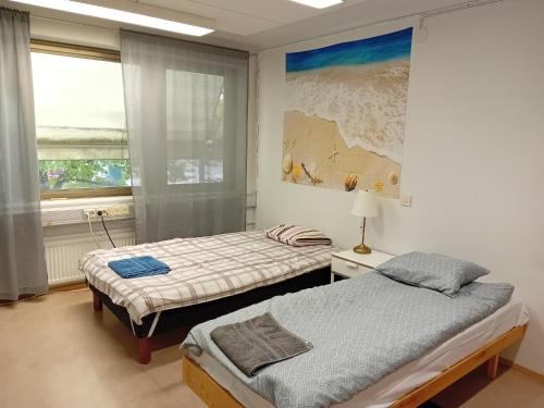 two twin beds in a room with a window at Hostel Yöpöllö in Kouvola
