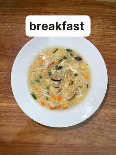 a white bowl of chicken noodle soup on a table at Hoàng Huy Hotel in Cat Ba