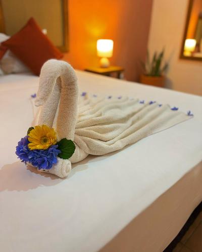 a towel on a bed with a flower on it at Hotel International House Riviera Maya in Playa del Carmen