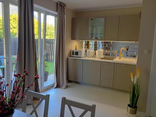 a kitchen with white cabinets and a large window at Deluxe Apartament z tarasem i parkingiem na wyłączność in Ciechanów