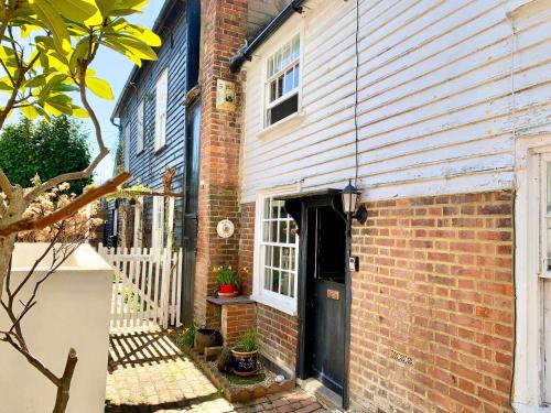 a brick house with a black door and a building at Watts Cottage, Cosy 2 bed, historical home in Bexhill