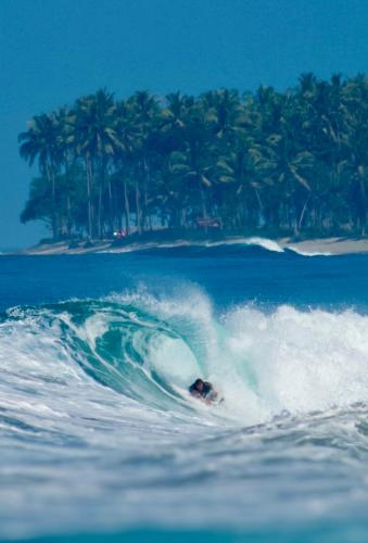 a person riding a wave on a surfboard in the ocean at Krui Surfing in Wainapal