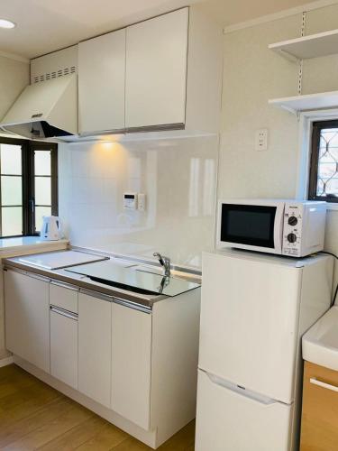 a white kitchen with a microwave and a refrigerator at Hiregasaki, Nagareyama 2号 CB0439 in Nagareyama