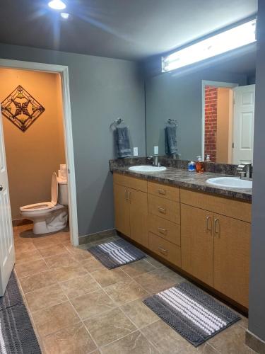 a bathroom with two sinks and a toilet and a mirror at Washington Loft in Saint Louis