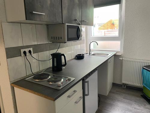 Una pequeña cocina con estufa y microondas. en Pension & Monteurzimmer - Free Parking & 24h Check-in Bielefeld, en Bielefeld