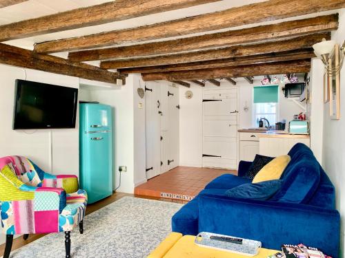a living room with a blue couch and a kitchen at Watts Cottage, Cosy 2 bed, historical home in Bexhill