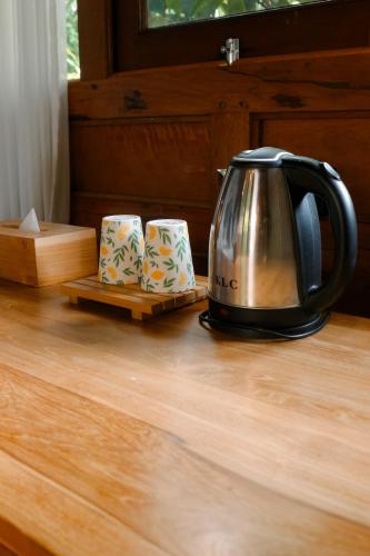 a tea kettle sitting on a wooden table with two teapees at Nishiyama Wooden House in Ambengan