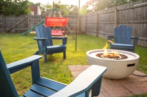 a fire pit with two blue chairs and a playground at Heated Pool, Hot Tub, Walk to Town, Games! in South Haven