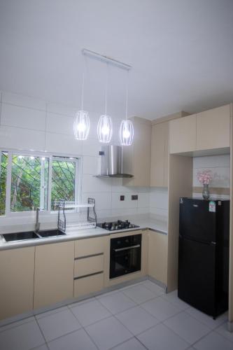 a kitchen with white cabinets and a black refrigerator at Subree Luxury Villas- Nyali in Mombasa