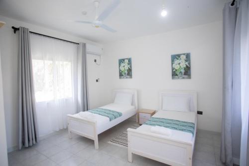 a bedroom with two beds and a window at Subree Luxury Villas- Nyali in Mombasa