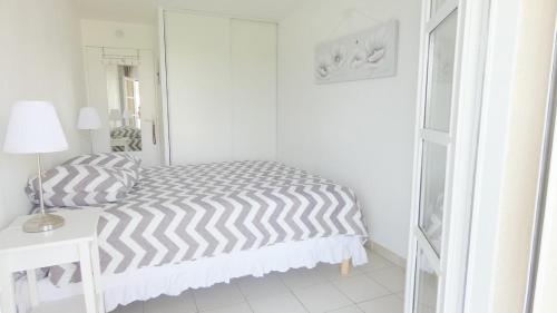 ein weißes Schlafzimmer mit einem Bett, einer Lampe und einem Tisch in der Unterkunft Golfe de saint-tropez a 50 m de la plage in Gassin