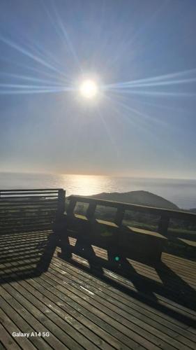 a bench on the beach with the sun in the sky at Refúgio Farol Ponta do Catalão - Imbituba/SC in Imbituba