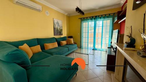 Una sala de estar con un sofá verde y una cocina. en #343 Villa with Pool & Jacuzzi by Home Holidays, en Vale de Pedras