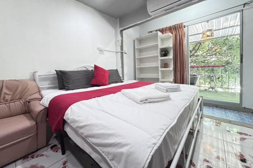a bedroom with a bed and a couch and a window at Sunshiny-BB Hostel in Bangkok