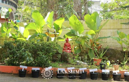 a person sitting in a garden with plants at Lakshmi Ayurveda & Yoga Retreat in Kovalam