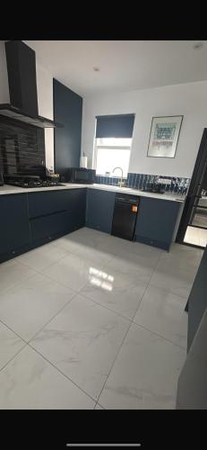 a large kitchen with blue cabinets and a tile floor at City Centre Chic in Bangor
