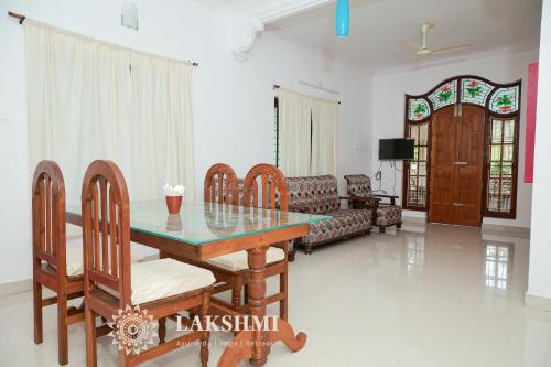 a living room with a table and chairs and a couch at Lakshmi Ayurveda & Yoga Retreat in Kovalam