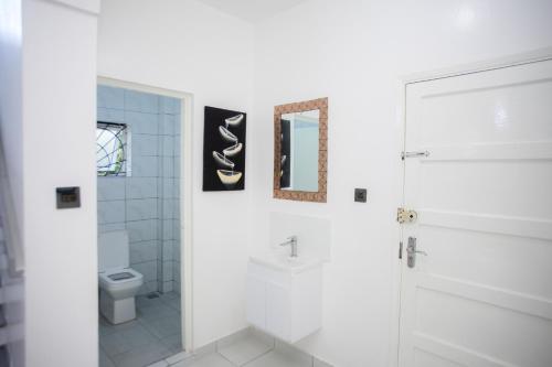 a white bathroom with a toilet and a mirror at Subree Luxury Villas- Nyali in Mombasa