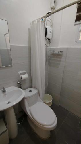 a white bathroom with a toilet and a sink at Danielle's Haven in Naga