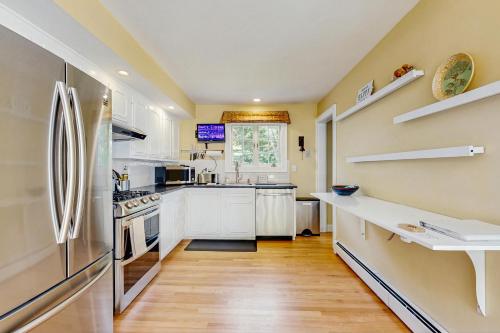 a kitchen with white cabinets and a stainless steel refrigerator at 10-Minute Walk to the Beach 