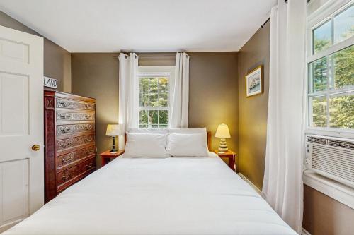 a bedroom with a large bed and two windows at 10-Minute Walk to the Beach 