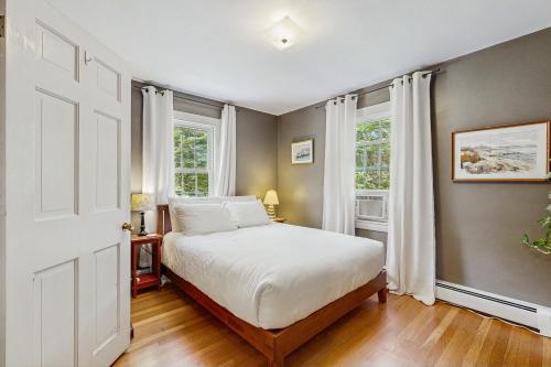 a bedroom with a bed and two windows at 10-Minute Walk to the Beach 