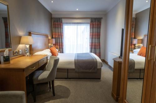 a hotel room with a bed and a desk and a mirror at Dale Hill Hotel in Ticehurst