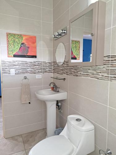 a bathroom with a white toilet and a sink at Casa palmera in San Juan del Sur