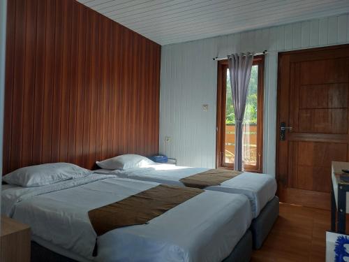 a bedroom with two beds and a large window at Istana Bromo Resort in Bromo