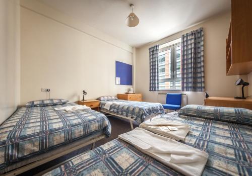 a room with three beds and a window at LSE Bankside House in London