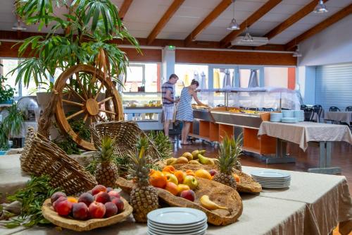 ein Tisch mit Obst darauf und Menschen in der Küche in der Unterkunft Village Vacances Passion La Bayette in Le Pradet