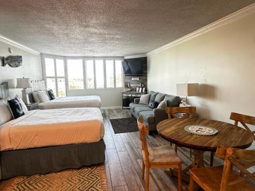 a bedroom with a bed and a couch and a table at Renovated Beach Front Condo - Top Of The Gulf 302 in Panama City Beach