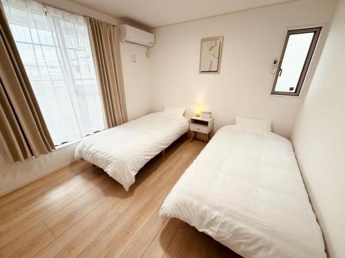 two beds in a room with a window at ZZOKIAI 橙霞 30-seconds walk to the seaside!4LDK maximun 10 people! in Itoman