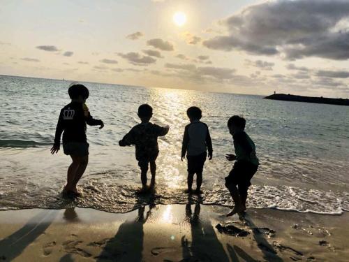 a group of four boys playing on the beach at ZZOKIAI 橙霞 30-seconds walk to the seaside!4LDK maximun 10 people! in Itoman
