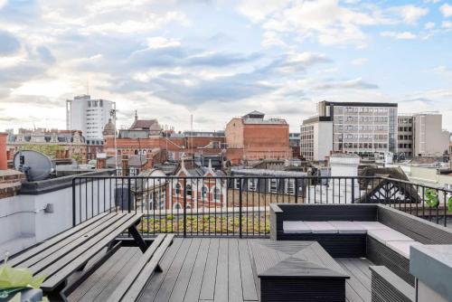 a balcony with a bench and a view of a city at Stunning 1-bed Soho Apartment With Rooftop Terrace in London