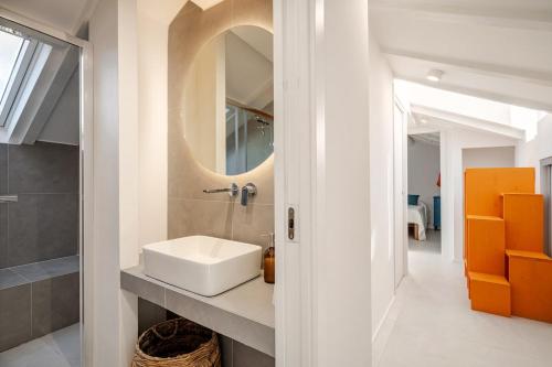 een witte badkamer met een wastafel en een spiegel bij La Mansarda di Via Niella in Savona
