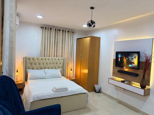 a bedroom with a bed and a flat screen tv at Luxury 2-bed w 24h light in Magodo GRA Phase 2 in Sagisa