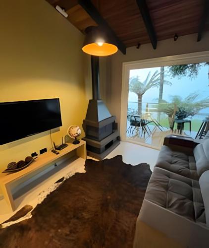 a living room with a couch and a tv and a fireplace at Cabana romântica com Jacuzzi ao lado de Gramado in Igrejinha