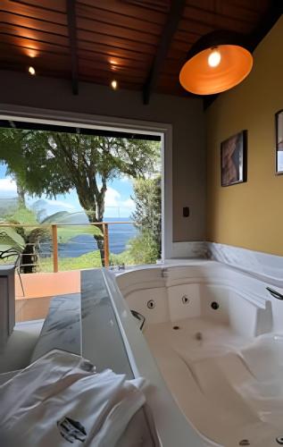 a room with a bath tub and a large window at Cabana romântica com Jacuzzi ao lado de Gramado in Igrejinha