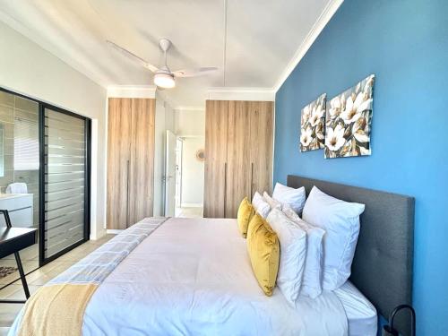 a bedroom with a large white bed with yellow pillows at Beach Paradise in Ballito
