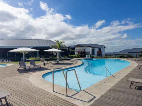 a pool with tables and chairs and umbrellas at Blissnest in Ballito