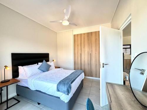 a bedroom with a bed with a ceiling fan and a mirror at Blissnest in Ballito