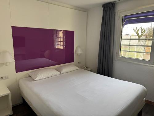 a bedroom with a white bed and a purple wall at Tulip Inn Beaune in Beaune