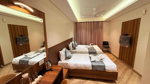 a hotel room with two beds and a mirror at Grand Sea Way in Chennai