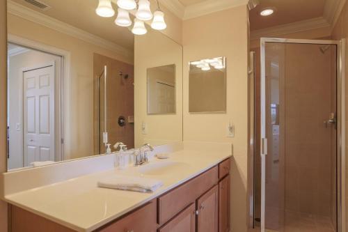 une salle de bain avec un lavabo, un miroir et une douche dans l'établissement Second Floor River Strand Condo Overlooking the Golf Course - Sunny Life, à Marsh Island